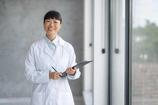 istock A joyful woman in lab coat, smiling with clipboard 2224965990