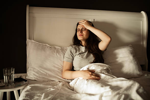 istock A woman lying in bed, feeling unwell and sick. 2224966972
