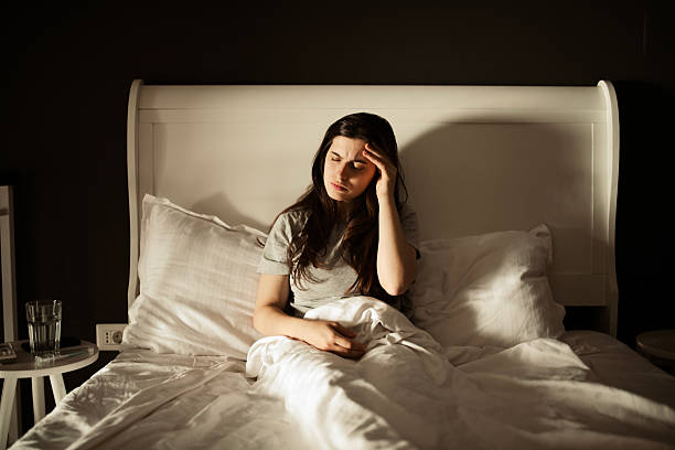 istock A woman lying in bed, feeling unwell and sick. 2224966979