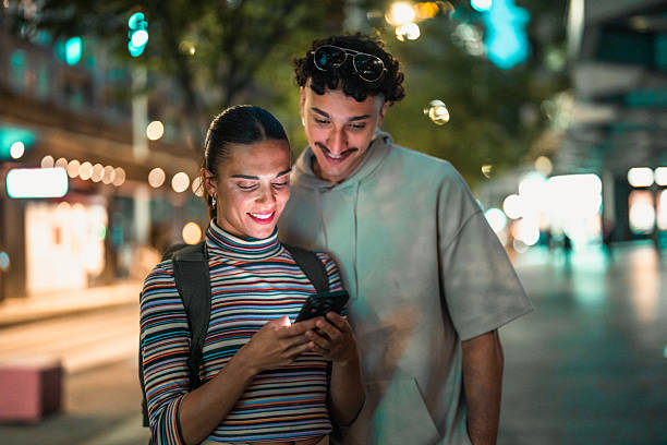 istock Hispanic Couple Using Smartphone on City Street at Night 2224967383