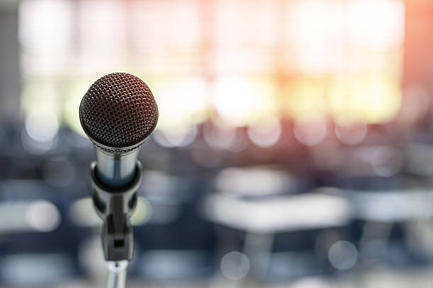 istock Microphone voice speaker in seminar classroom, lecture hall, town hall meeting or conference forum in educational business event for coaching host or teacher with audiences or students seats 2224967414