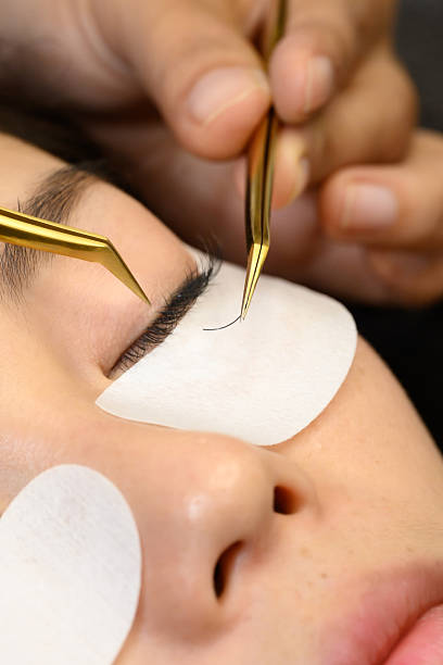 istock Close up of beauty salon technician applying individual eyelash extensions with precision tweezers 2224990966