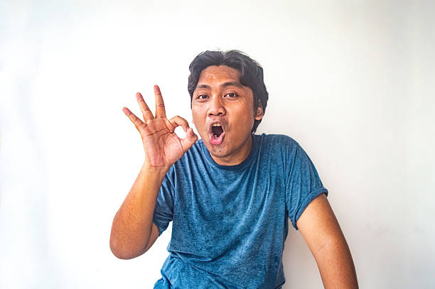 istock A man in a blue shirt is making an OK hand gesture against a plain white background. The image is simple and clear, making it suitable for various uses such as advertisements, blogs, or social media 2224993857
