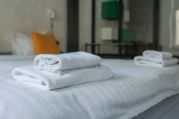 istock Soft white towels neatly folded on clean white bedding in a modern minimalist bedroom with blurred yellow pillows in the background 2224997959