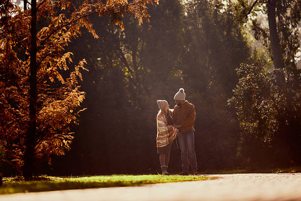 Happy couple communicating while walking during autumn day at the park. Copy space.