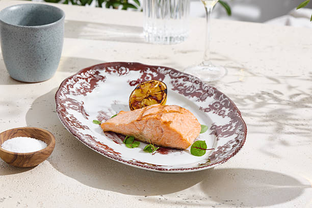 istock Grilled salmon steak with charred lemon, bright daylight, overhead composition 2224999399