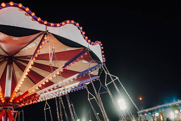 istock Swing ride with lights glowing at night in amusement park 2225002104
