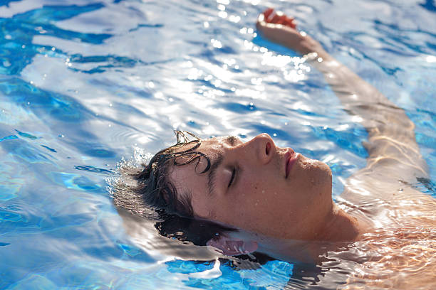 istock Young man relaxing floating in a swimming pool 2225003754