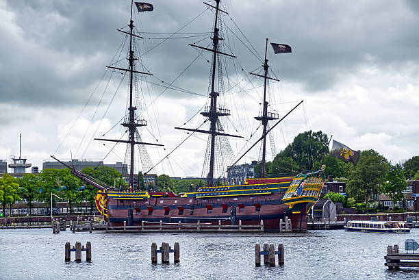 istock Historic three master sailing vessel docked in amsterdam harbor, flags billowing against moody cloudscape, capturing nautical heritage 2225004407