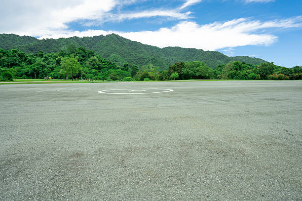 istock Empty helicopter landing pad with asphalt with green mountain forest background providing emergency medical transport access to remote wilderness areas. Helipad platform at dam infrastructure site. 2225007782