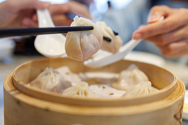 istock Sharing Steamed Xiaolongbao Dumplings with Chopsticks and Spoons 2225008851