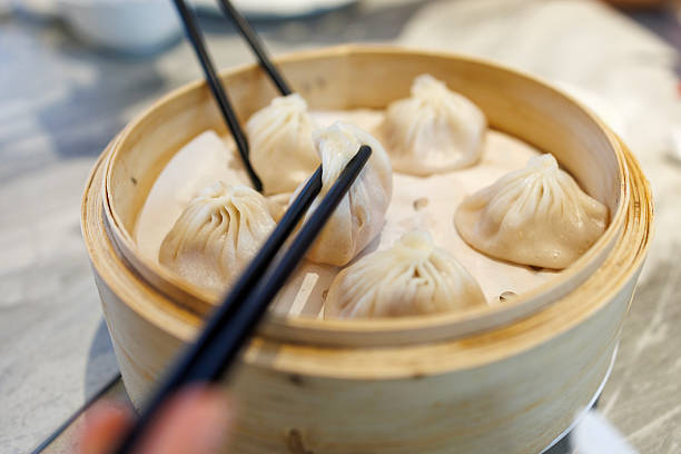 istock Sharing Steamed Xiaolongbao Dumplings with Chopsticks and Spoons 2225009087