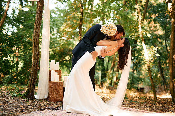 istock Groom kissing bride during romantic wedding ceremony in forest 2225009122
