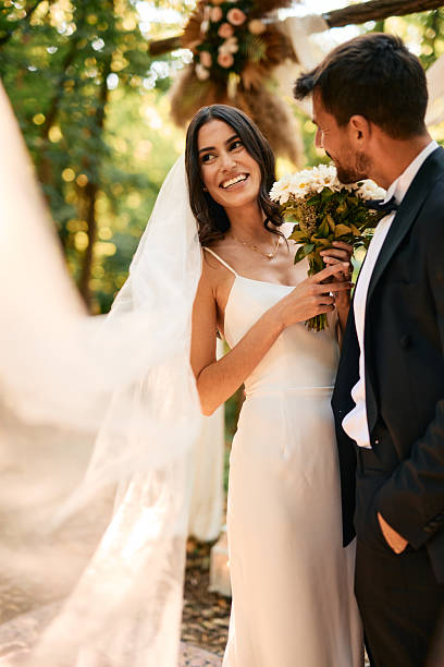 istock Happy bride holding bouquet looking at groom during wedding ceremony 2225009478
