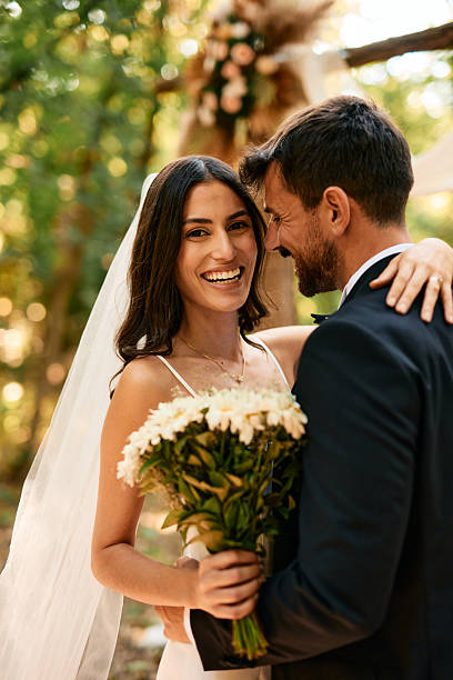istock Happy bride holding bouquet embracing groom in forest wedding ceremony 2225009499