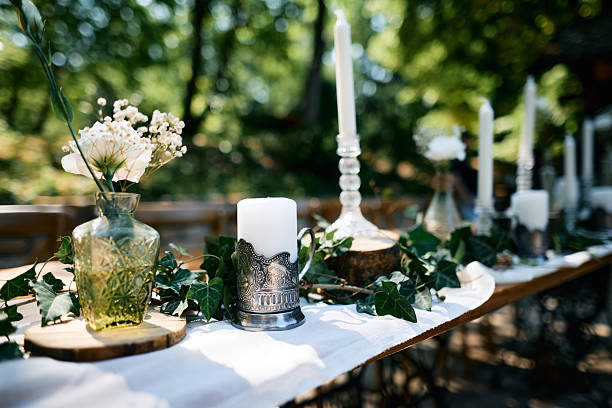 Wedding table setting decorated with candles, flowers and ivy in the forest