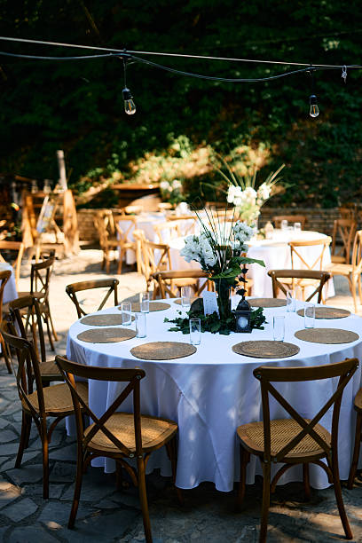istock Outdoor wedding reception with round tables and cross-back chairs featuring white tablecloth and flower centerpiece 2225010011