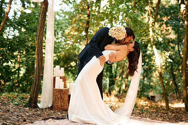 istock Groom kissing bride during wedding ceremony in the forest 2225010300