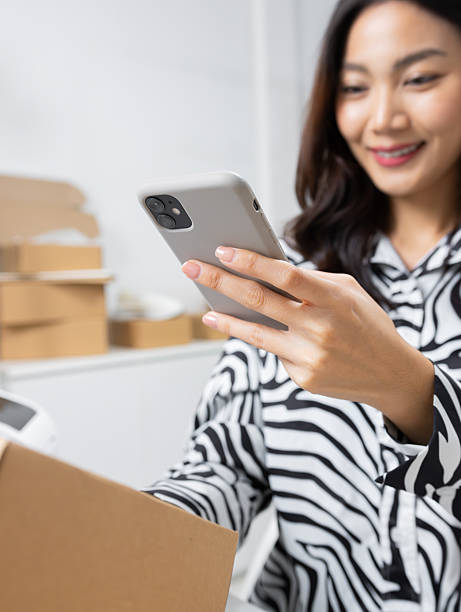 istock Asian Small Business owner using smartphone scanning QR Code on Parcel box, preparing product to shipping. 2225010326
