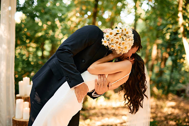 istock Groom kissing bride while holding her and bending her over in a forest 2225010360