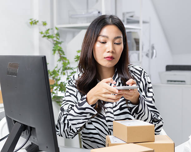 istock Asian Small Business owner using smartphone scanning QR Code on Parcel box, preparing product to shipping. 2225010377