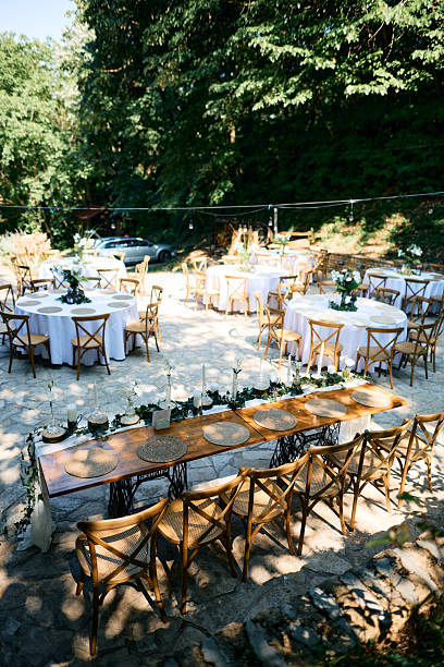 istock Wedding reception taking place in a forest clearing with round tables and a long table 2225010684