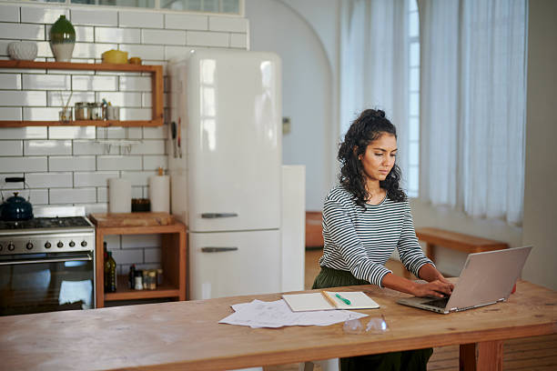 istock Female small business owner working remotely on laptop in modern kitchen 2225011099