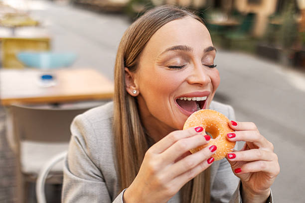 istock Young businesswoman eating a donut 2225013322