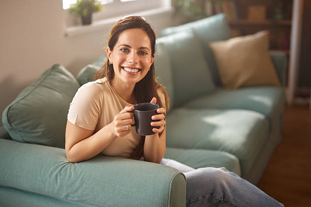istock Smiling woman relaxing on sofa with mug 2225014654