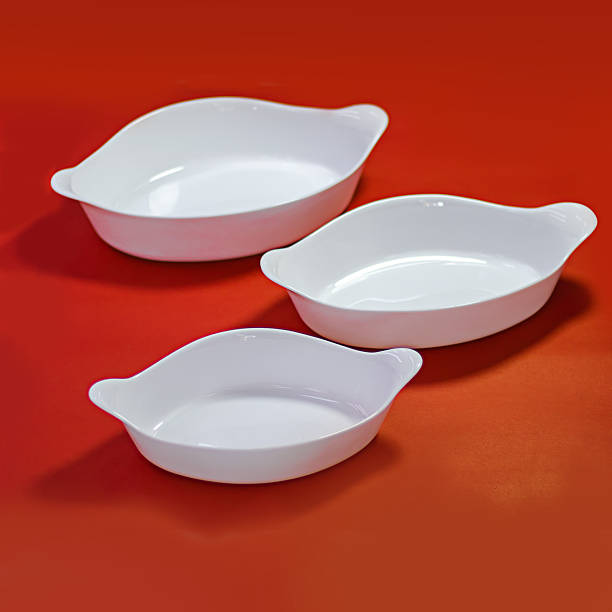 istock Set of three white ceramic baking dishes on a bold red background for kitchenware brands. 2225017197