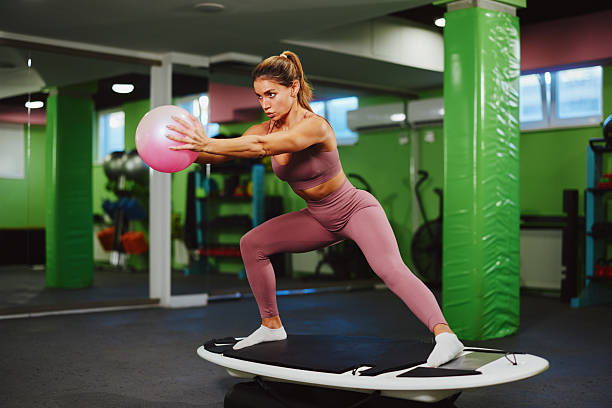 istock Fitness instructor using balance board and pilates ball for functional training in modern gym 2225018707
