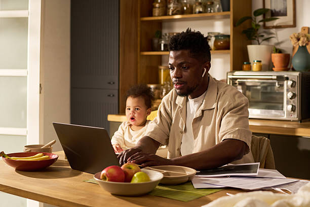 istock Young Black Father Multitasking with Laptop and Infant Daughter during Paternity Leave 2225018980