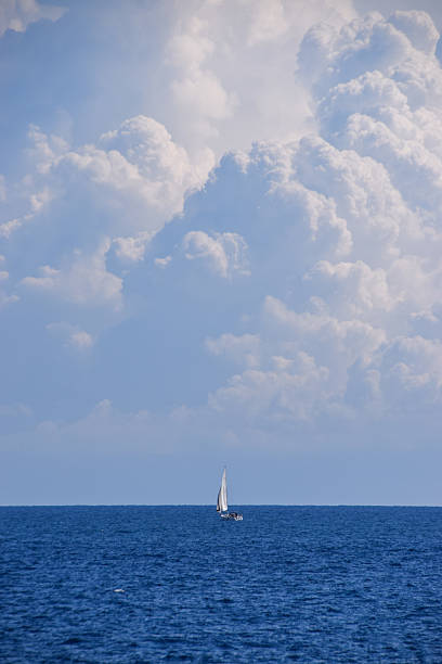 istock Dramatic clouds and a sailboat on the sea on the horizon 2225019324