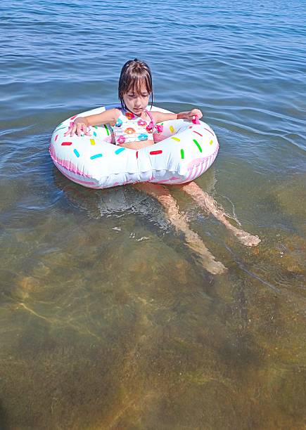 istock Little girl on inflatable donut shaped ring 2225026850