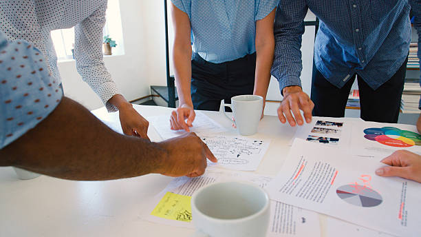 istock Close Up Of Multi-Cultural Business Team Standing Around Table Discussing Documents In Office 2225037111