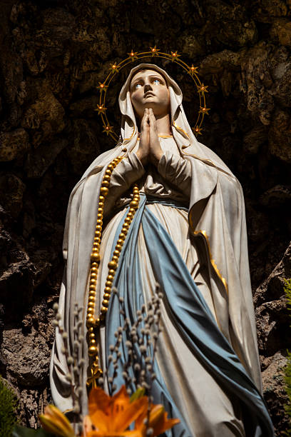 Ancient white statue of Virgin Mary against blue sky with free copy space for text.