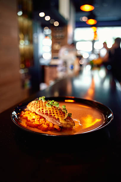 Exquisite gourmet dish: grilled chicken, waffle garnish, elegant dining ambiance, culinary delight