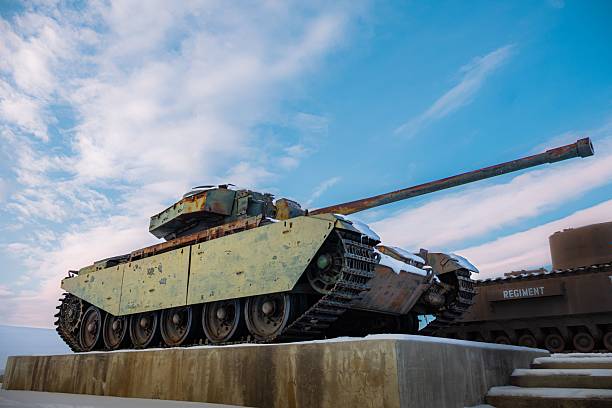 An old military tank is displayed outdoors under a bright blue sky, showcasing its historical significance.
