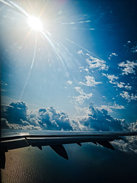 Breathtaking aerial view from an airplane\nwindow, showcasing a sun-drenched sky with\nuffy white clouds stretching over a vast\nexpansion of the ocean. The wing of the aircraft is\nvisible in the foreground. Perfect for themes\nof travel, freedom, adventure, and the beauty\nof the natural world seen from above.