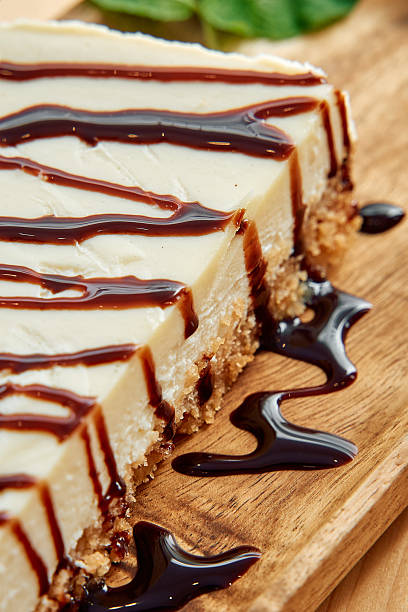 istock Delicious cheesecake slice with rich chocolate drizzle on wooden board 2225046906