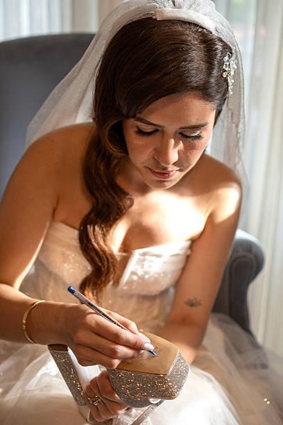 Young bride writing her single friends names on shoe indoors