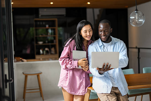 istock Multinational couple enjoying their morning routine, smiling and using laptop and tablet at home 2225050189