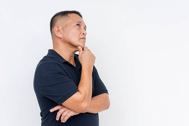 istock A middle-aged man looking pensive and unsure while posing against a white background, conveying thought and contemplation. Copyspace on the right. 2225054422