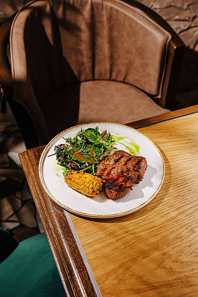 istock Grilled meat with salad and corn served on a plate in a cozy restaurant 2225054959