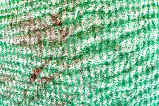 Dirty old unclean green microfiber cloth with grease stains and cat hair. Grunge and rough surface of fabric texture background.