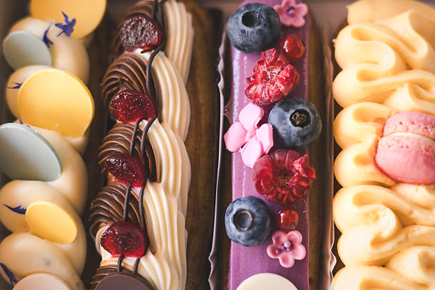 istock Delicious eclairs with fresh berries and macarons beautifully displayed in a bakery box. A close-up of colorful eclairs, adorned with fresh berries, and decorative frosting. Creamy sweets and treats. 2225057270