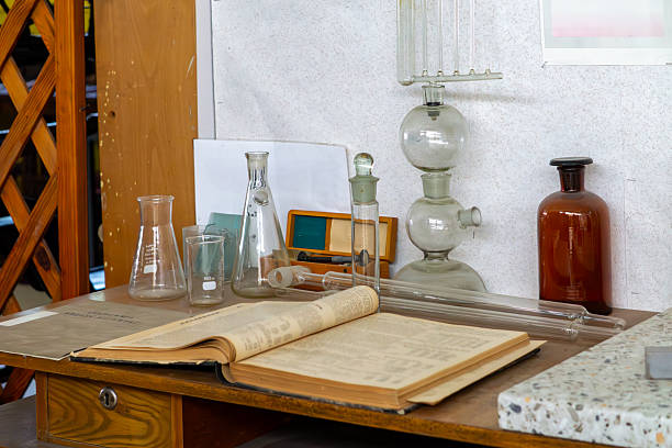 istock table in an abandoned laboratory with an open book, glass flasks, pipettes, and vintage lab apparatus. The scene captures an old research space with retro scientific equipment. 2225058672