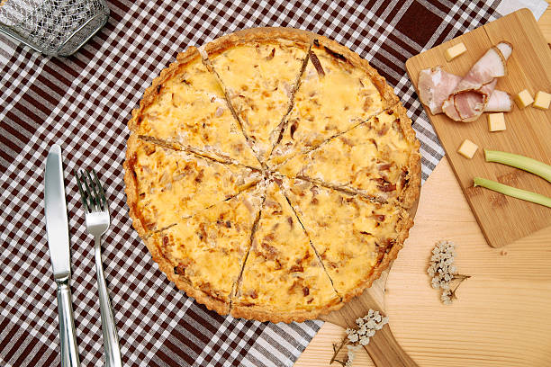 istock Savory quiche with ham, cheese, and onions on wooden board and checkered tablecloth 2225060390