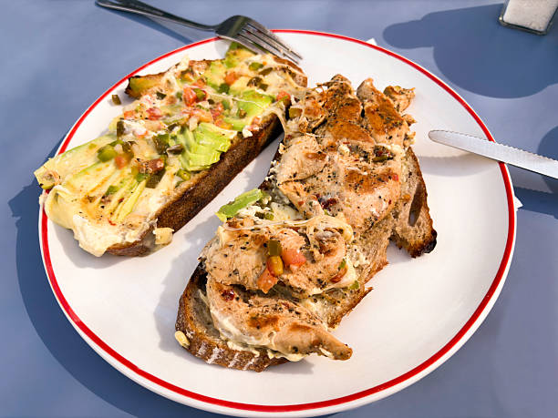 Spicy chicken sandwich on a plate with avocado, salad and cheese on wholewheat bread.