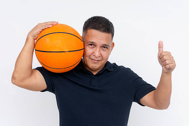 istock A confident short middle-aged Asian man making a thumbs up sign while holding a basketball on his shoulder. 2225062015